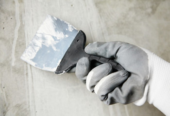 abstract photo of wall finishing work, trowel in the hands of a worker at a construction site, decorative repair
