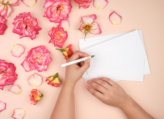 Plakat girl holds in her left hand a white pen and signs envelopes on a peach background