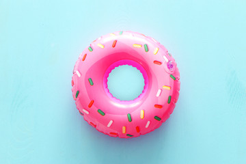 Inflatable donut ring over blue wooden background - obrazy, fototapety, plakaty