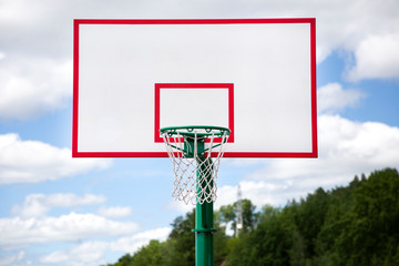 Basketball hoop on the street with blue cloudy sky on the background. Outdoor sport activity and streetball concept.