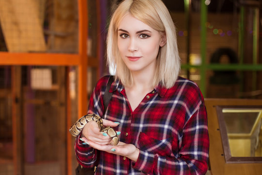 A beautiful blond woman is holding a small royal python in her hands. Contact zoo.