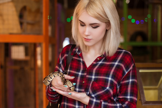 A beautiful blond woman is holding a small royal python in her hands. Contact zoo.