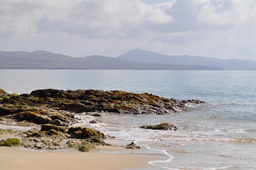 Rocky ocean beach with mountains on background. Costa Calma, Fuerteventura, Canary Islands