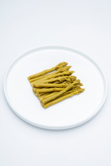 Asperges vertes sur assette blanche en studio