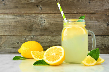 Homemade lemonade in a mason jar glass with lemons. Side view on a rustic wood background. - obrazy, fototapety, plakaty