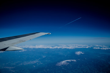 View from the plane to the mountains and clouds. In the distance the plane takes off