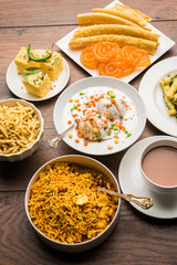 Group of Gujarati snacks like jalebi-fafda, thepla, khaman dhokla, aloo bhujiya, khandvi,khakra, dahi vada, gathiya with hot tea