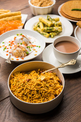 Group of Gujarati snacks like jalebi-fafda, thepla, khaman dhokla, aloo bhujiya, khandvi,khakra, dahi vada, gathiya with hot tea