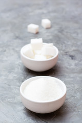 Concept advantages of granulated sugar over refined sugar. Two types of sugar in white bowls on the table, standing next to each other