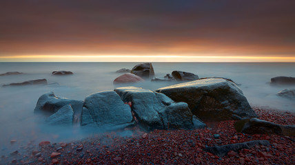 Beautiful sunrise in the Lake Superior lake shore beach with rocks long exposure