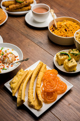 Group of Gujarati snacks like jalebi-fafda, thepla, khaman dhokla, aloo bhujiya, khandvi,khakra, dahi vada, gathiya with hot tea