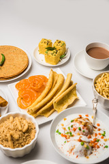Group of Gujarati snacks like jalebi-fafda, thepla, khaman dhokla, aloo bhujiya, khandvi,khakra, dahi vada, gathiya with hot tea
