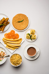 Group of Gujarati snacks like jalebi-fafda, thepla, khaman dhokla, aloo bhujiya, khandvi,khakra, dahi vada, gathiya with hot tea
