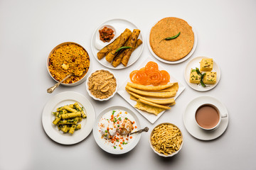 Group of Gujarati snacks like jalebi-fafda, thepla, khaman dhokla, aloo bhujiya, khandvi,khakra, dahi vada, gathiya with hot tea