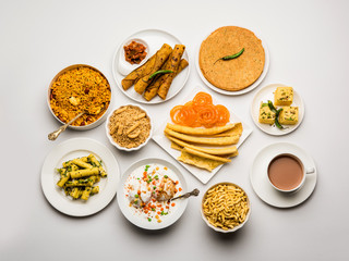 Group of Gujarati snacks like jalebi-fafda, thepla, khaman dhokla, aloo bhujiya, khandvi,khakra, dahi vada, gathiya with hot tea
