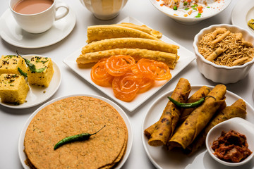 Group of Gujarati snacks like jalebi-fafda, thepla, khaman dhokla, aloo bhujiya, khandvi,khakra, dahi vada, gathiya with hot tea