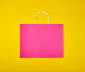 rectangular pink paper shopping bag with a white handle on a yellow background