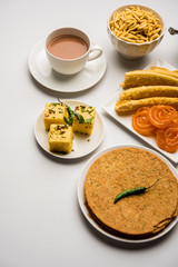 Group of Gujarati snacks like jalebi-fafda, thepla, khaman dhokla, aloo bhujiya, khandvi,khakra, dahi vada, gathiya with hot tea