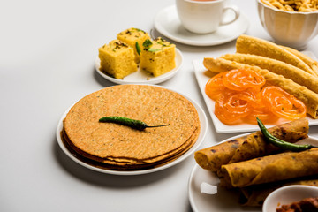 Group of Gujarati snacks like jalebi-fafda, thepla, khaman dhokla, aloo bhujiya, khandvi,khakra, dahi vada, gathiya with hot tea