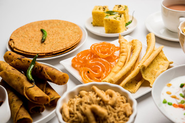 Group of Gujarati snacks like jalebi-fafda, thepla, khaman dhokla, aloo bhujiya, khandvi,khakra, dahi vada, gathiya with hot tea