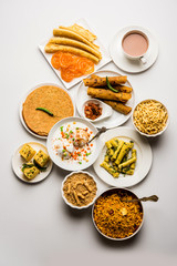 Group of Gujarati snacks like jalebi-fafda, thepla, khaman dhokla, aloo bhujiya, khandvi,khakra, dahi vada, gathiya with hot tea