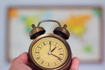 Alarm clock on hand with retro world map background.