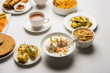 Group of Gujarati snacks like jalebi-fafda, thepla, khaman dhokla, aloo bhujiya, khandvi,khakra, dahi vada, gathiya with hot tea