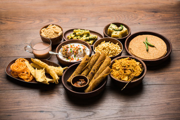 Group of Gujarati snacks like jalebi-fafda, thepla, khaman dhokla, aloo bhujiya, khandvi,khakra, dahi vada, gathiya with hot tea