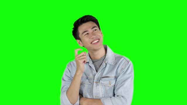 Young Asian man thinking in the studio and looks getting an idea. Shot in 4k resolution with green screen background