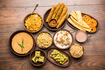 Group of Gujarati snacks like jalebi-fafda, thepla, khaman dhokla, aloo bhujiya, khandvi,khakra, dahi vada, gathiya with hot tea