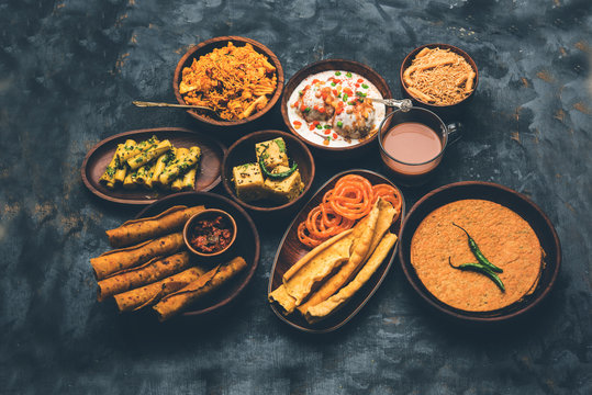 Group of Gujarati snacks like jalebi-fafda, thepla, khaman dhokla, aloo bhujiya, khandvi,khakra, dahi vada, gathiya with hot tea