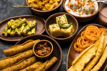 Group of Gujarati snacks like jalebi-fafda, thepla, khaman dhokla, aloo bhujiya, khandvi,khakra, dahi vada, gathiya with hot tea