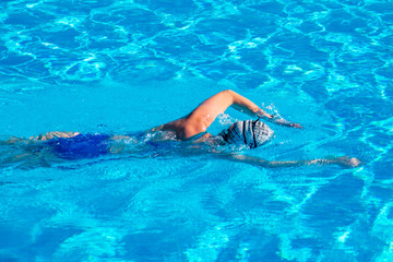 Woman with swimsuit swimming on a blue water pool.