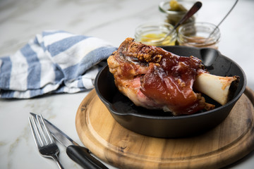 Gegrillte Schweinefleisch Haxe in gusseiserne Pfanne auf Holzbrett mit Cornichons, süßen und...