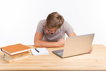People and education concept - Funny student man sitting at the wooden table with laptop and books