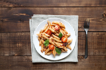 Italian pasta with tomatos on dark wood table. Top view