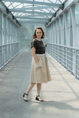 Beautiful stylish woman with backpack, smiling, happy, street style, beige skirt, green t-shirt.