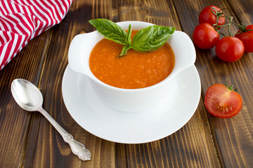 Tomato soup in the white bowl on the brown  wooden background.Closeup.