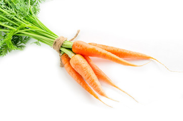 Fresh carrots with green foliage on white background.