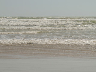 Background. Sea waves with foam ranning on the sandy beach.