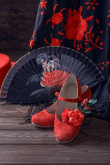 Beautiful and bright accessories for flamenco dance on a wooden background. Shawl, hat, fan, shoes, castanets and a flower for the hair.