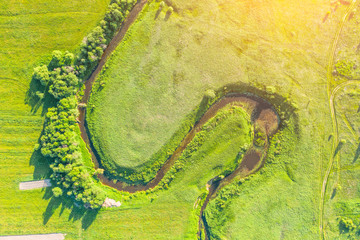 Aerial landscape countryside of winding small river, stream in green field, top view sunset meadow.