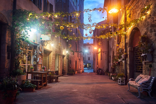Cafes in a narrow street in the evening in the city of Grosseto, Italy.