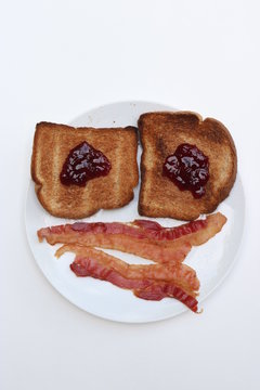 Portrait of a happy meal; jelly toast and bacon arranged as a smiley face