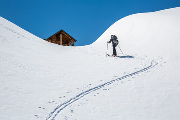Skier skinning uphill, hiking toward a backcountry ski hut in the Rocky Mountains of British...