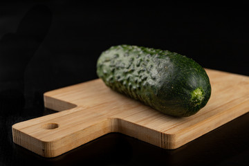 Cucumber on a wooden chopping board. Tasty vegetables on the kitchen table.