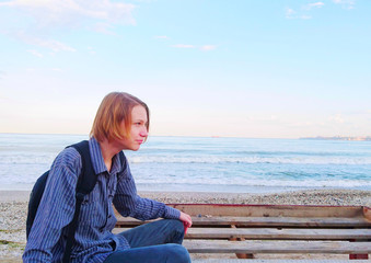 Teen schoolboy sitting on the beach