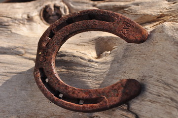 old rusty horseshoe on a white wooden background