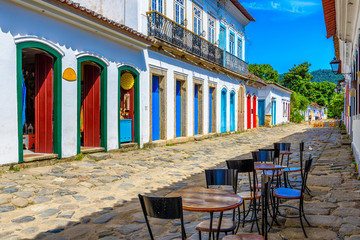 Fototapeta na wymiar Street with tables of cafe in historical center in Paraty, Rio de Janeiro, Brazil. Paraty is a preserved Portuguese colonial and Brazilian Imperial municipality