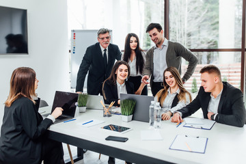 Staff meeting. Group of   young modern people in smart casual wear discussing something while working in the creative office . Business time..